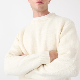 Model wearing Edwin Crew Neck jumper in off white, chunky ribbed knit, arms crossed, relaxed oversized fit.