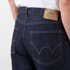 Model wearing Edwin 3049 Loose Jeans in blue rinsed denim, close-up of back pockets with gold stitching detail.