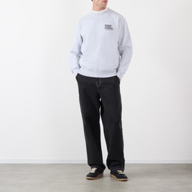 Model wearing Edwin grey marl cotton sweatshirt with small chest graphic, styled with black wide-leg trousers and dark trainers.