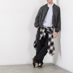 Model wearing Edwin Grey Marl cotton sweatshirt with dark bomber jacket, black trousers and checked shirt tied at waist.