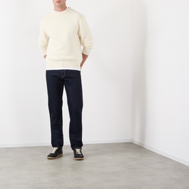 Model wearing Edwin 3049 Tapered Jeans in blue rinsed with a cream crewneck sweatshirt and dark lace-up shoes.