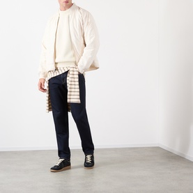 Model wearing Edwin 3049 Tapered Jeans in blue rinsed, styled with a cream sweatshirt, quilted jacket and checked shirt tied at the waist.