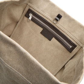 Lemaire Belted Tote Bag in dark linen, interior view showing zipped pocket, embossed logo patch and silver-tone hardware detail.