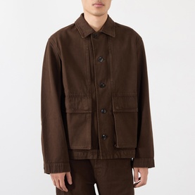Model wearing Lemaire Flap Pocket Overshirt in brown with point collar, front button fastening, and large flap pockets, styled with brown trousers.