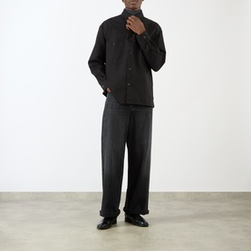 Model wearing Lemaire black cotton casual shirt with mandarin collar, styled with wide-leg dark trousers and black leather shoes.