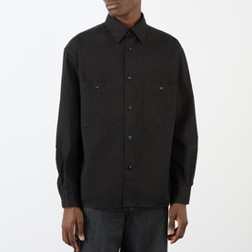 Model wearing Lemaire black cotton casual shirt with twin chest pockets and button-front fastening, styled with dark jeans.