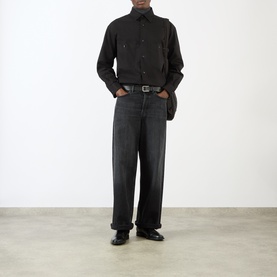 Model wearing Lemaire black cotton casual shirt with wide-leg dark grey jeans, black leather belt and black loafers.