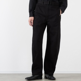 Model wearing Lemaire black cotton casual trousers with belted waist and wide straight leg, styled with black leather shoes.