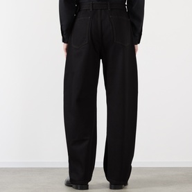 Model wearing Lemaire black casual trousers in cotton, shown from behind with wide-leg silhouette and clean finish.