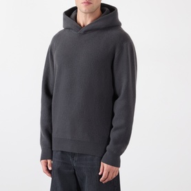 Model wearing Lemaire dark grey cashmere hoodie with textured knit finish and relaxed fit, styled with dark trousers.