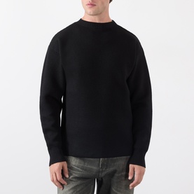 Model wearing Lemaire black wool crew neck sweater with relaxed fit, styled with grey distressed jeans