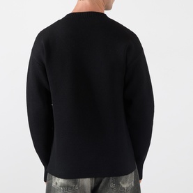 Model wearing Lemaire black wool crew neck jumper, back view, styled with distressed grey jeans.