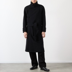 Model wearing Lemaire black wool coat with asymmetric button fastening, high collar, and self-tie belt, styled with black wide-leg trousers.