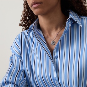 Model with Mettle & Bloom To The Moon & Back Necklace in silver, platinum-plated with zirconia stones on curb chain, styled with blue striped shirt