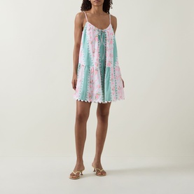 Model wearing Loose Scallop Trim Dress in pistachio/multi printed cotton with tiered skirt and scallop hem, styled with gold heeled sandals
