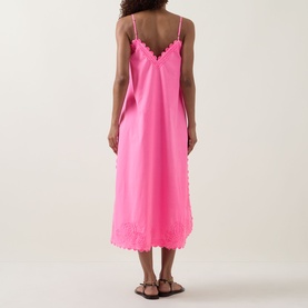 Model wearing Juliet Dunn Hot Pink cotton midi dress with scalloped hem and neckline, thin straps, back view, styled with tan sandals
