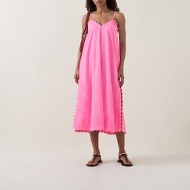 Model wearing Juliet Dunn Hot Pink cotton midi dress with scalloped hem trim and side panels, styled with tan flat sandals