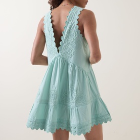 Model wearing Embroidered Low Back Mini Dress in Hot Pink cotton with scalloped trims, low V-back, embroidered detail and flared mini skirt