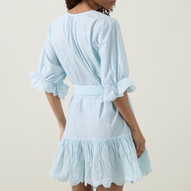Model wearing Poplin Tie Waist Dress in Ice Blue/White with ruffled sleeves, tie waist, and tiered ruffled hem, back view.