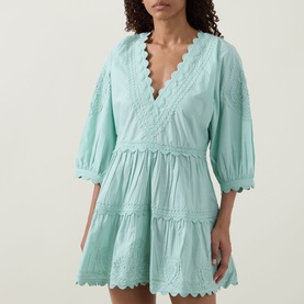 Model wearing Tiered Scalloped Dress in pistachio cotton, featuring V-neckline, scalloped trim, and tiered skirt with broderie anglaise detail