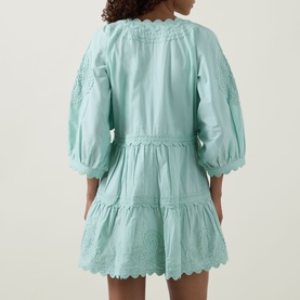 Model wearing Tiered Scalloped Dress in pistachio, rear view showing tiered cotton skirt, scalloped hem and cuffs, balloon sleeves
