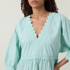 Model wearing Tiered Scalloped Dress in pistachio, featuring V-neckline with lace scalloped trim and tiered cotton silhouette