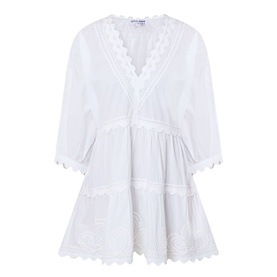 White cotton mini dress with V-neckline, scalloped lace trim, floral embroidery, tiered skirt, and three-quarter sleeves by Juliet Dunn