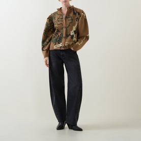 Model wearing Urban Aran brown merino wool cardigan with abstract pattern, styled with dark wide-leg jeans and black loafers