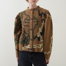 Model wearing Urban Aran brown merino wool cardigan with abstract camo intarsia pattern, button front, and collarless neckline