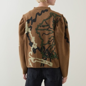 Model wearing Urban Aran brown merino wool cardigan, back view showing bold abstract intarsia design in green, cream and black