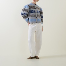 Model wearing Urban Aran grey merino wool cardigan with blue and brown fair isle pattern, styled with white wide-leg trousers and taupe loafers