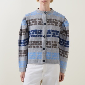 Model wearing Urban Aran grey merino wool cardigan with blue and brown geometric pattern, button front, and puff sleeves, styled with white jeans