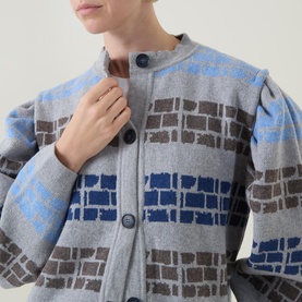 Model wearing Urban Aran grey merino wool cardigan with blue and taupe brick-pattern jacquard, button fastening, close-up detail shot
