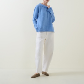 Model wearing Urban Aran blue merino wool knit jumper with relaxed fit, styled with white tapered trousers and tan loafers.