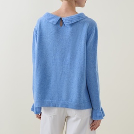 Model wearing Urban Aran blue merino wool knit jumper, back view showing collared neckline with keyhole detail and ribbed cuffs