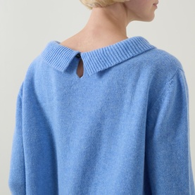 Model wearing Urban Aran blue merino wool knit jumper, rear view showing ribbed collar with keyhole button detail