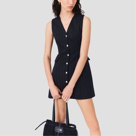 Model wearing Maje Womens French Dress in black, sleeveless V-neck mini with button front, styled with a black structured handbag