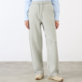 Model wearing Ami Paris grey cotton wide-leg joggers with drawstring waist, styled with a light blue top and cream trainers.