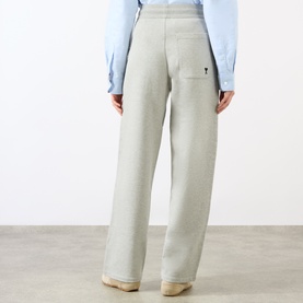 Model wearing Ami Paris grey cotton wide-leg trousers, rear view, with small logo detail on back pocket, styled with a light blue shirt.