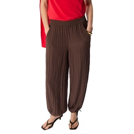 Model wearing Whistles brown crinkle wide-leg trousers with elasticated waist and tie ankles, styled with a red top.