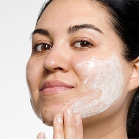 Model with Clinique Liquid Facial Soap Oily Refill applied to cheek, shown as a white lather on skin