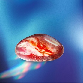 FAO Discovery multi-coloured translucent oval toy stone with red and white swirl detail, on a blue gradient background