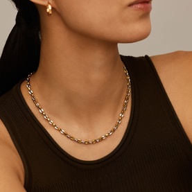Model with Missoma gold and silver mixed-metal chain-link necklace, styled with matching hoop earring and dark ribbed vest top.