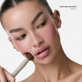 Model with Poco Beauty Universal Cream Stick in Bare It All blush shade applied to cheeks using a fluffy brush