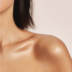 Poco Beauty Sun Care result shown on model's shoulder and d&eacute;colletage, with a natural sun-kissed, luminous glow finish