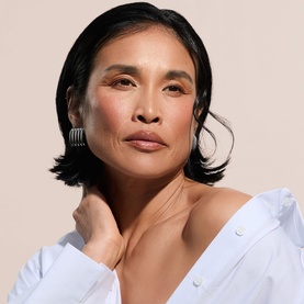 Model with Poco Beauty Sun Care complexion finish, wearing a white shirt and silver statement earrings with delicate chain necklace
