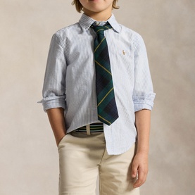 Model wearing Ralph Lauren light blue stripe children's shirt with green tartan tie and beige chinos