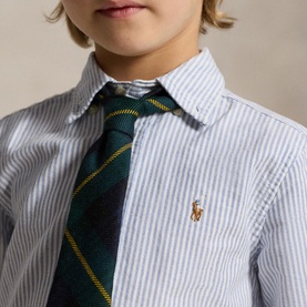 Model wearing Ralph Lauren children's light blue stripe shirt with gold pony logo, styled with a green tartan tie