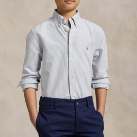 Model wearing Ralph Lauren light blue stripe Oxford shirt with button-down collar and embroidered pony logo, styled with navy chinos.