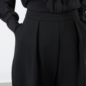 Model wearing Rohe black wide-leg trousers in viscose-elastane blend, with pleated front detail and fitted waistband, styled with black top.